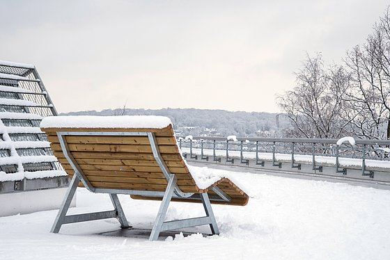 Bank hinter der Mensa mit einem schneebedeckten Blick ins Tal