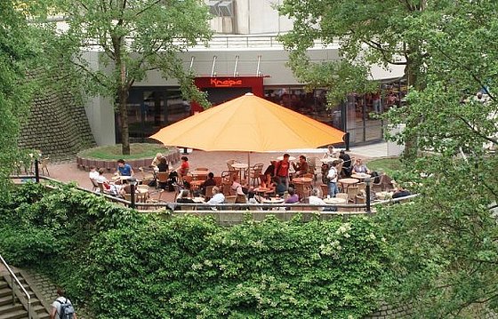 Blick durch die Bäume auf die Terasse der Kneipe